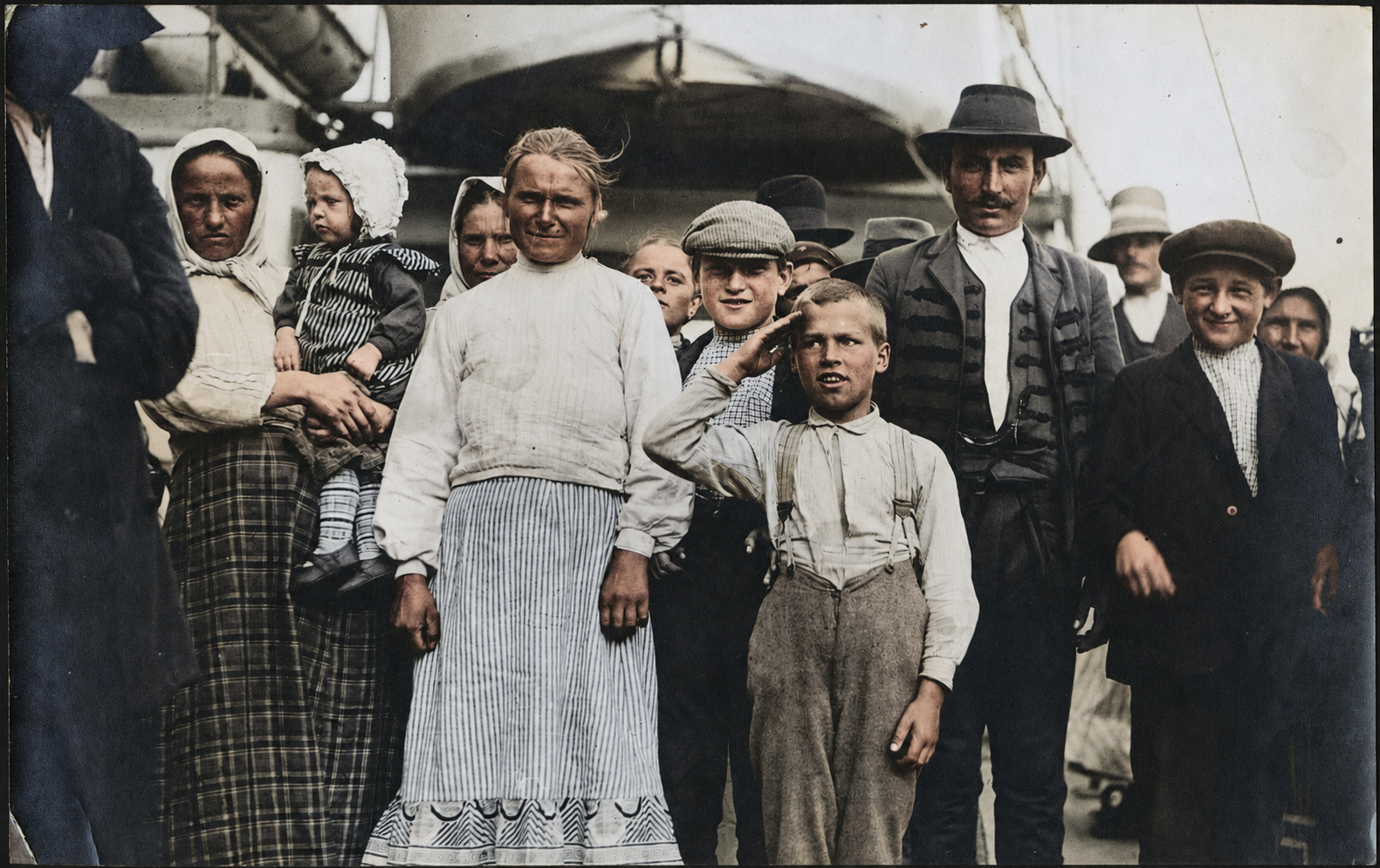 Immigrant families aboard a ship in Boston Harbor, including a boy raising his hand in salute